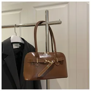 Detail einer braunen glänzenden Ledertasche mit Doppelreißverschluss und Goldmetall-Details