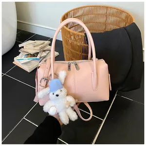 Detailed view of a pink lychee texture handbag with a cute rabbit plush charm