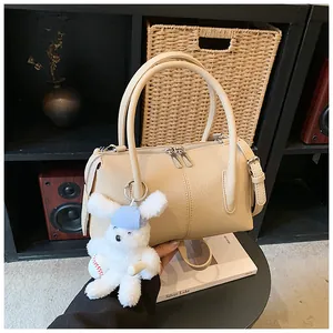 Detail of off-white lychee grain leather Boston bag with a cute white bunny plush pendant