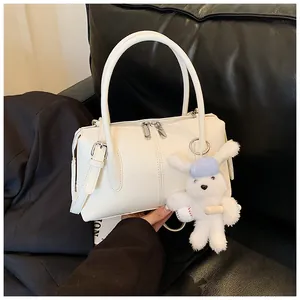 Close-up of a white lychee grain boston bag with double handles and a rabbit charm