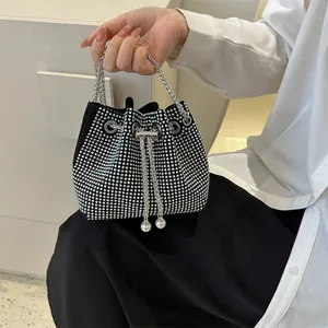 Macro view of sparkly rhinestone bucket bag featuring silver chain and pearl drawstrings