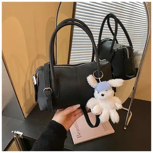 Close-up of black lychee grain leather Boston bag with a cute white rabbit pendant charm