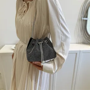 Close-up of sparkling rhinestone bucket bag with silver chain and white pearl drawstring