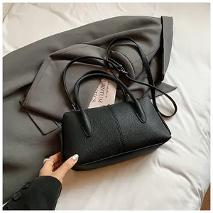 Detail of black lychee grain leather handbag with dual handles and adjustable strap