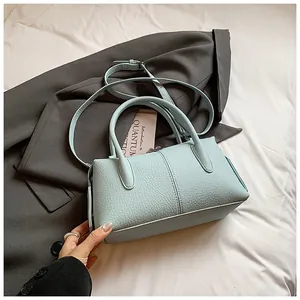 Detailed shot of light blue litchi pattern leather handbag on stylish grey blazer