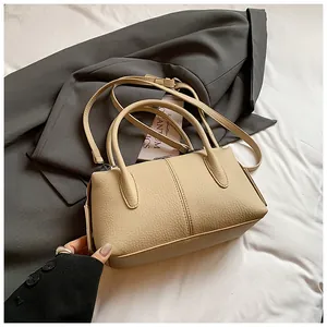 Close-up of beige lychee grain PU leather handbag with fine vertical stitching and dual handles