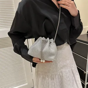 Detail of silver rhinestone bucket bag featuring drawstring chain and white pearl charms