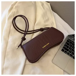 Detail of dark brown crocodile pattern PU leather underarm bag with gold metal hardware