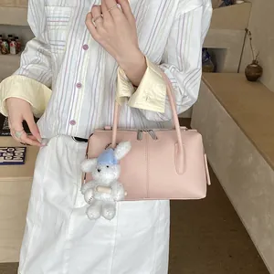 Pink lychee grain leather handbag with a plush bunny charm in a cozy indoor setting