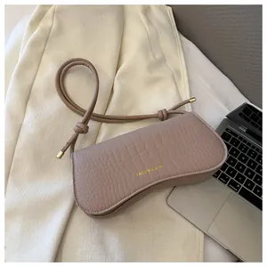 Close-up of taupe crescent bag with crocodile texture and gold hardware detail