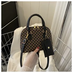 Close-up of retro shell handbag with geometric monogram pattern and gold metal zippers