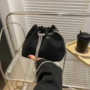 Detail view of the black rhinestone bucket bag showing the pearl chain and drawstring closure