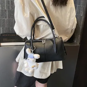 Chic black litchi textured Boston handbag with a cute rabbit pendant and crossbody strap