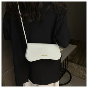 Detail of white PU leather underarm bag with wavy base and golden text on black suit
