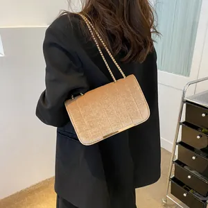 Goldbraune Samt-Umhängetasche mit vertikalen Nähten und Goldkette auf schwarzem Blazer