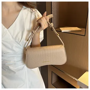 Detailed view of apricot crocodile embossed texture and golden metal knot on shoulder bag