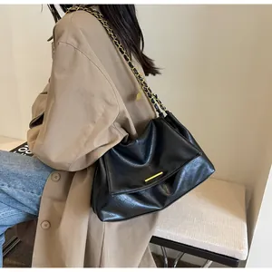 Detail view of the black crossbody bag featuring a golden chain strap and leather texture