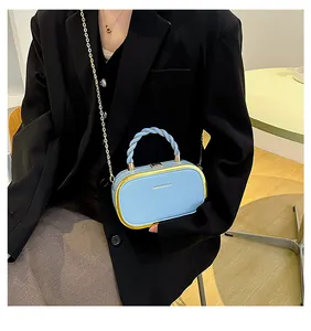 Close-up of sky blue chain box bag with twisted handle and gold frame details