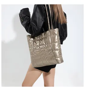 Detail of golden quilted tote bag with square embroidery and metallic finish