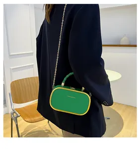 Close-up of green chain box bag with golden metal frame and FASHION & BAG text