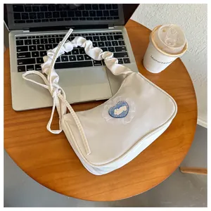 Détail d'un sac à bandoulière blanc crème avec un patch lapin mignon sur un bureau