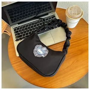 Détail du sac en toile noire avec bandoulière plissée et écusson lapin sur la table