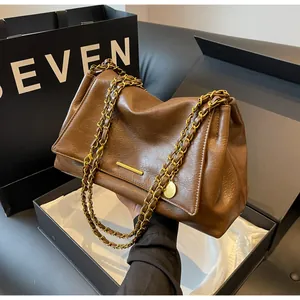 Detail of caramel brown leather handbag with gold chain strap and metallic texture