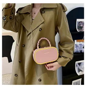 Detail of a pink and yellow box bag with a twisted handle and gold chain strap