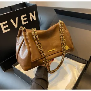 Detailed shot of a brown leather shoulder bag with gold chains in a premium gift box