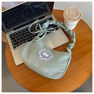 Détail d'un sac à bandoulière vert menthe avec écusson lapin en cœur et anse froncée