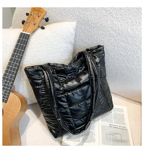 Detail of black quilted tote bag with glossy nylon texture and lattice stitching pattern