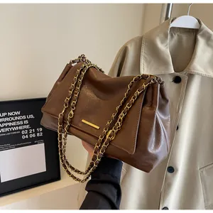 Close-up of brown litchi pattern leather bag with gold chain strap and metal trim