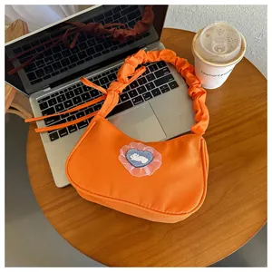 Détail du sac demi-lune orange avec écusson lapin coeur et poignée froncée chic