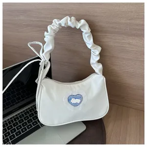 Détail de la poignée plissée et du patch cœur à carreaux bleus avec lapin sur sac blanc