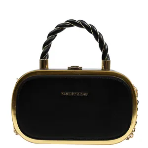 Close-up of black leather handbag with gold metal frame and woven handles detail