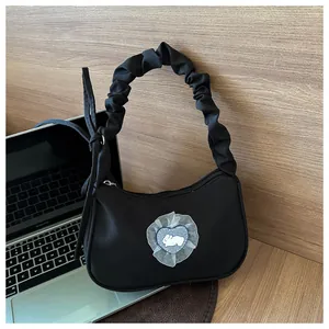 Sac croissant noir avec écusson lapin et poignée à volants sur un bureau en bois massif