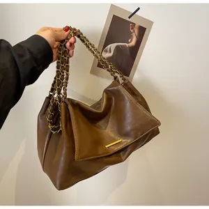 Detail of dark brown hobo bag featuring gold chain strap and textured leather finish