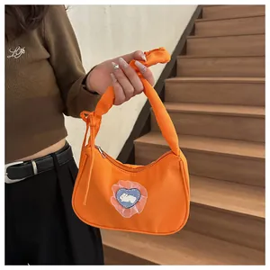 Détail du sac orange en tissu avec écusson lapin en cœur et poignée nouée design