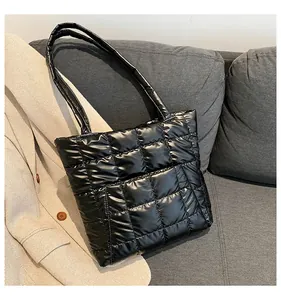Close-up of quilted black tote bag with glossy finish on a grey sofa background