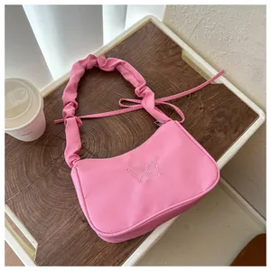 Detalle de bolso hobo rosa con bordado de mariposa y correa fruncida decorativa