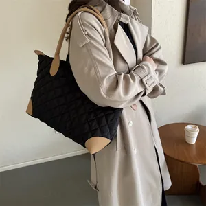 Détail du grand sac cabas matelassé en nylon noir avec des anses en cuir kaki contrastantes