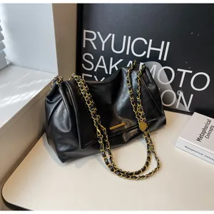 Close-up of black lychee grain faux leather handbag with golden metal chain straps