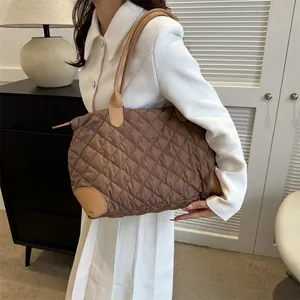 Vue détaillée d'un sac cabas marron matelassé porté avec un costume blanc élégant