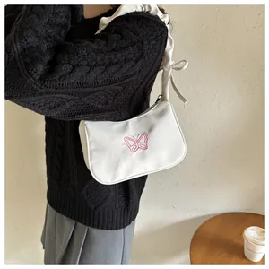 Detalle de bolso de hombro plisado blanco con delicado bordado de mariposa rosa