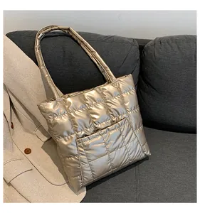 Detail of champagne gold quilted tote bag with square stitching on a grey sofa