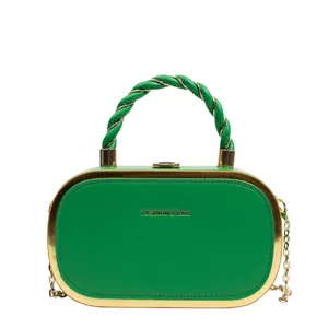 Close-up of vibrant green hard shell box bag with gold metal frame and twisted handle