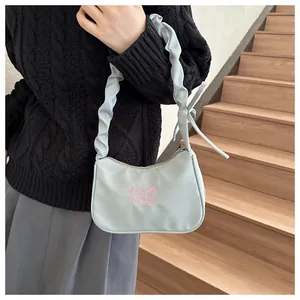 Detalle de bolso de hombro azul claro con bordado de mariposa rosa y correa fruncida