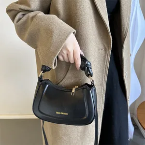 Détail d'un sac demi-lune noir avec poignée nouée et lettrage doré Tidal Dryness élégant