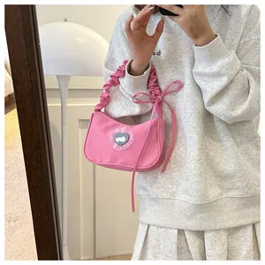 Gros plan du sac rose avec badge lapin coeur et détail de la poignée froncée