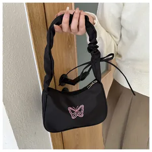 Dettaglio della borsa a spalla nera in nylon con ricamo a farfalla rosa e manico arricciato